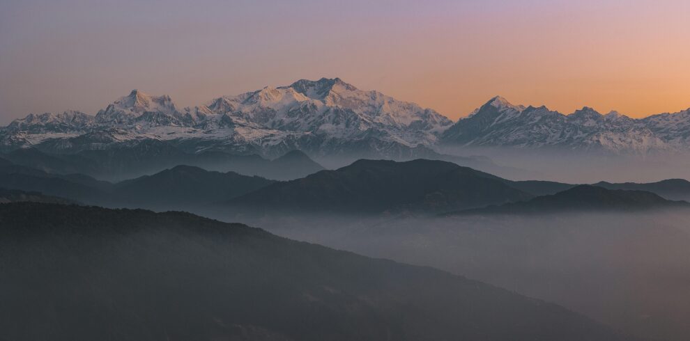 Beautiful sunrise view of the snow-covered Himalayas in Sikkip, India, with misty valleys and a scenic backdrop.